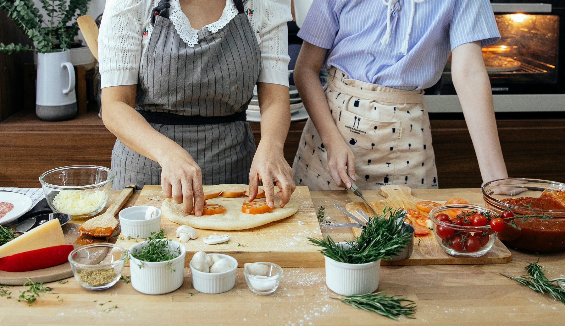 Crop women cooking pizza together